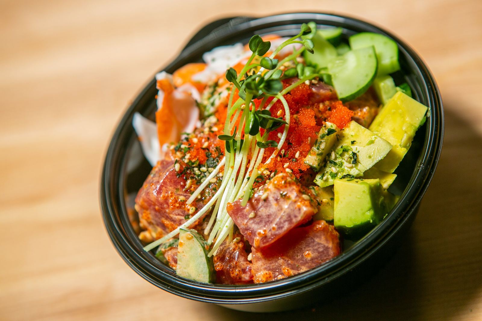 An overhead shot of a poke bowl with ahi, avocado and cucumber