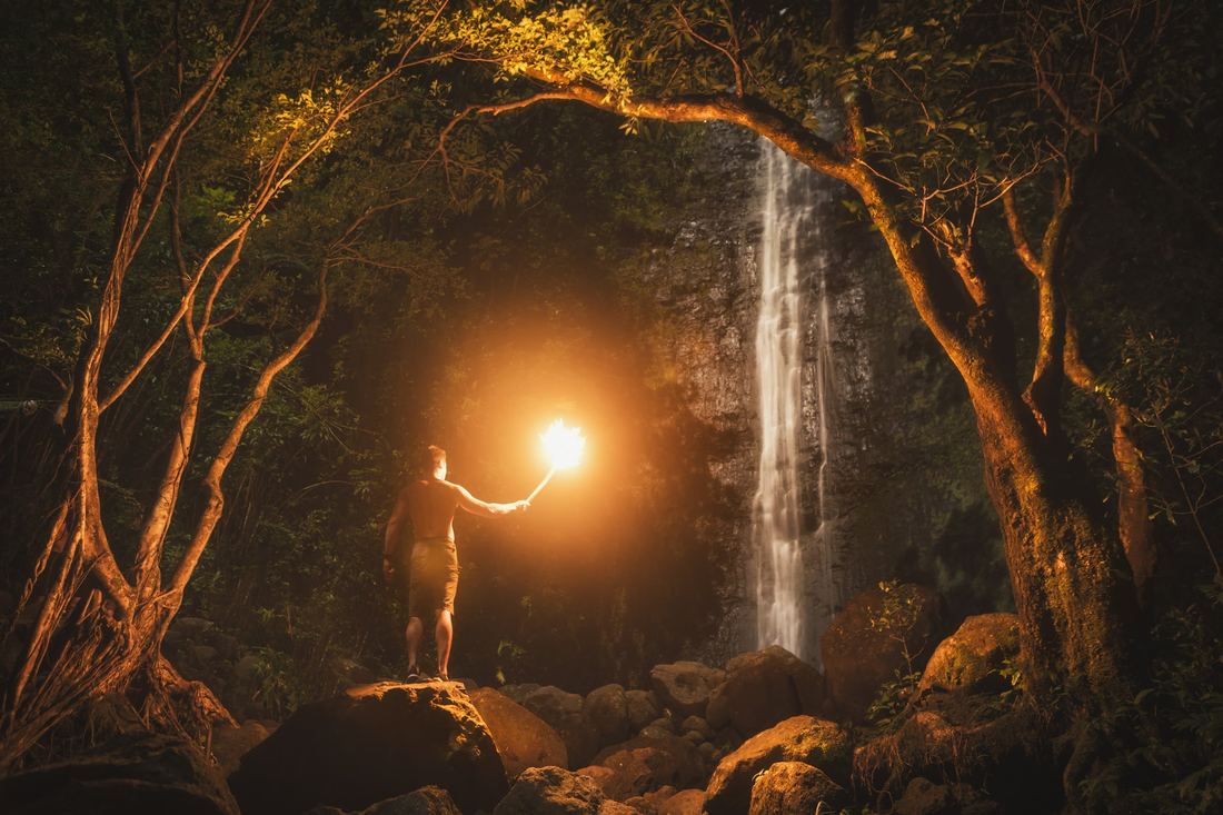 A hiker holding a light inside a waterfall grotto