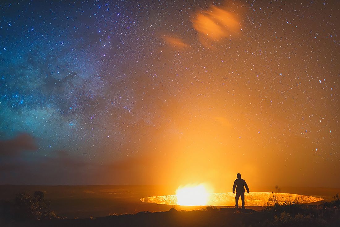 A figure silhouetted against a lava glow at night
