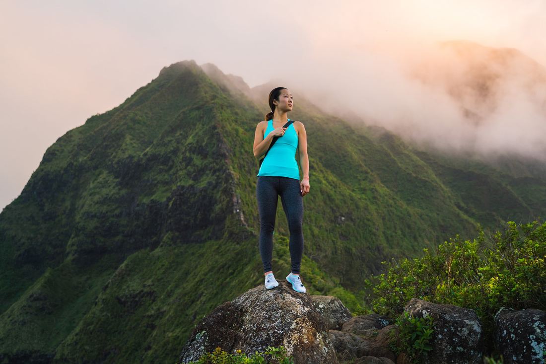 A hiker standing on a green summit in the clouds