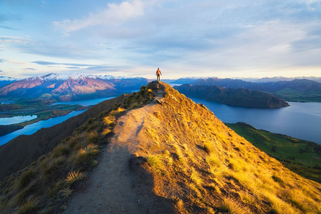 A hiker on a knife edge ridge at sunrise