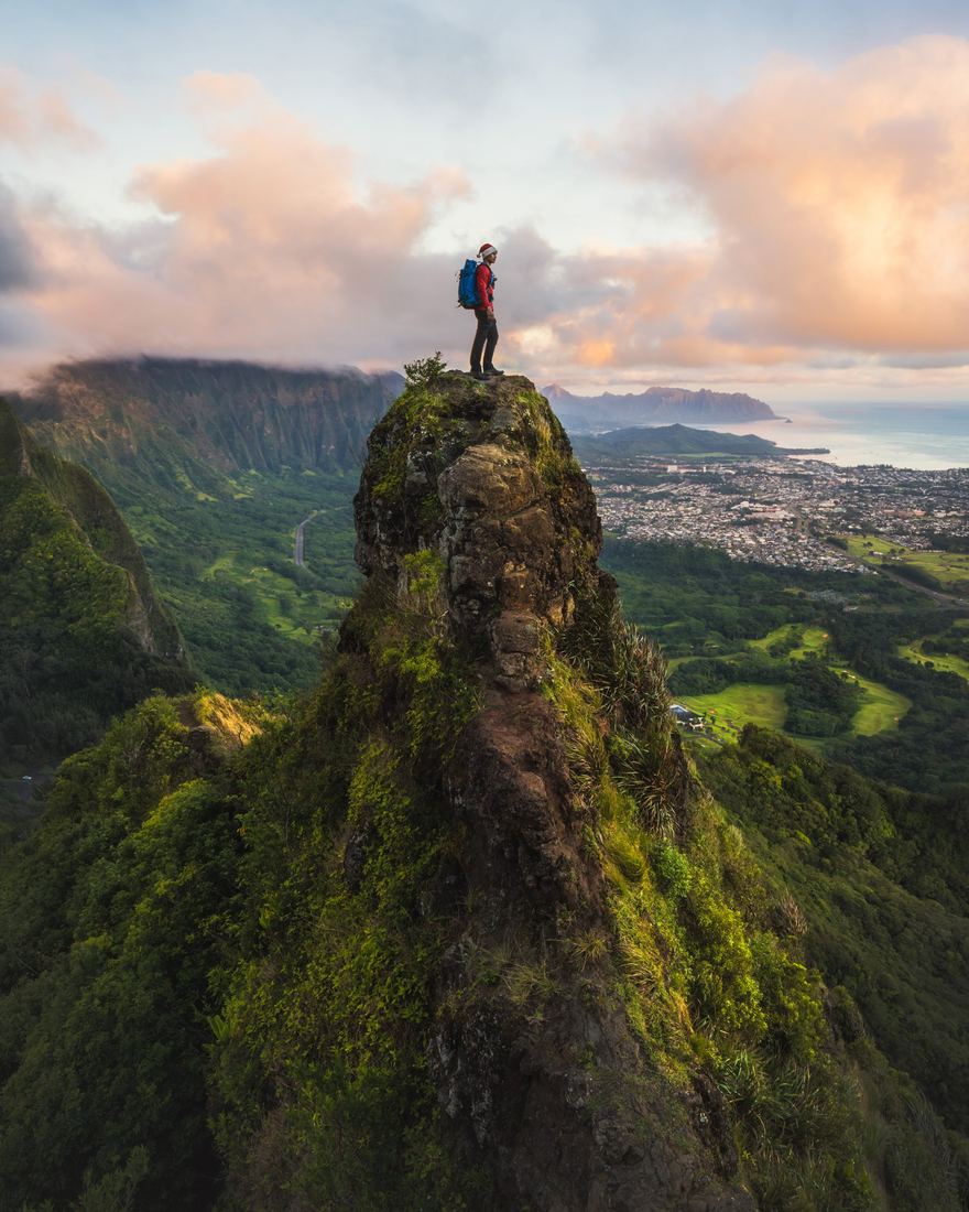 A hiker alone on a narrow peak above the clouds