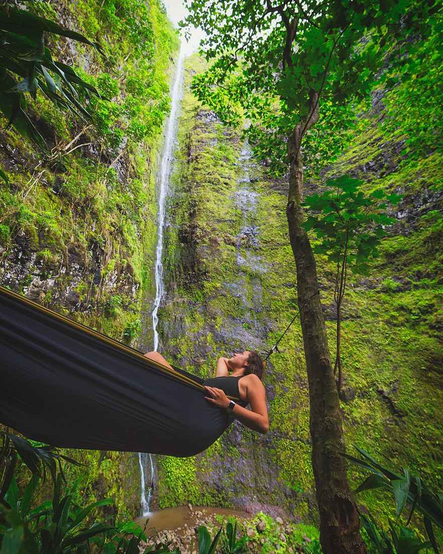 A hammock strung beside a waterfall in the forest