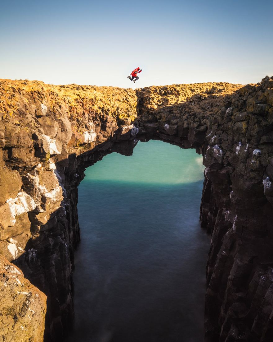 Aerial view of a sea arch with a figure standing on it